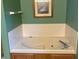 Bathroom featuring a large white soaking tub with wooden cabinets and tiled surround at 7664 Lincoln Trl, Plainfield, IN 46168
