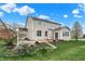 Tan two-story home featuring a sunroom and backyard patio and steps leading to the lawn at 7736 Eagle Point Cir, Zionsville, IN 46077