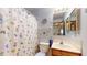 Bathroom with floral shower curtain, wall clock, mirror and wooden vanity at 8142 Bentley Farms Dr, Indianapolis, IN 46259