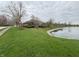 Picturesque waterfront property with lush green lawn and mature trees in a serene neighborhood at 1066 Woodridge, Brownsburg, IN 46112