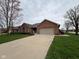 Single-story red brick home with a two-car garage, green lawn, and mature trees at 1066 Woodridge, Brownsburg, IN 46112