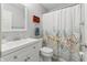 Bathroom with gray walls, floral shower curtain, white vanity, toilet, and red storage shelf at 10875 Santa Anita Ct, Carmel, IN 46280