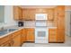 Close up of the kitchen with natural wood cabinetry, white appliances, and ample countertop space at 12319 Wolf Run Rd, Noblesville, IN 46060