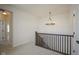 Upstairs landing area with modern chandelier, carpeted floors and dark wood railing at 13107 Pennington Rd, Fishers, IN 46037