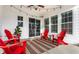 Relaxing covered back porch featuring string lights, ceiling fan, and comfortable red Adirondack chairs at 1401 Farmhouse Dr, Westfield, IN 46074