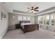 Neutral-toned main bedroom featuring a ceiling fan, carpet, and large windows for natural light at 14059 Knightstown E Dr, Carmel, IN 46033