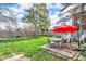 Spacious backyard with mature trees, lush green grass, and a patio with outdoor seating and red umbrella at 211 N Merrill St, Fortville, IN 46040