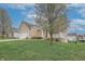 View of the tan, two-story house on a grassy hill with a quaint front porch and white trim at 2889 Grimes Way, Columbus, IN 47201