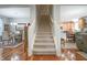 Bright foyer showcasing hardwood floors and a carpeted staircase with white banisters leading to the upper level at 2889 Grimes Way, Columbus, IN 47201