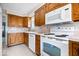Functional kitchen with oak cabinets, white appliances, a microwave, and tile flooring, ideal for preparing meals at 4711 Cornelius Ave, Indianapolis, IN 46208