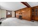 Comfortable living room featuring wood paneled walls, a fireplace, neutral carpet, and a built-in wooden cabinet at 4711 Cornelius Ave, Indianapolis, IN 46208