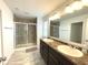 Bright bathroom featuring a double vanity, large mirror, and a glass-enclosed shower with grey tiling at 5115 Triple Crown Way, Indianapolis, IN 46237