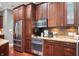 Kitchen featuring stainless steel appliances, dark wood cabinets, and granite countertops with stylish backsplash at 5202 Logan Ln, Indianapolis, IN 46250