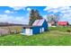 Blue storage barn with a white garage door and side entry surrounded by green lawn at 5442 W 400 N, Fairland, IN 46126