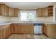 Well-lit kitchen features a stainless steel dishwasher, wooden cabinets, and a window overlooking the yard at 5442 W 400 N, Fairland, IN 46126