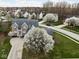 Stunning aerial view of a two-story brick home with beautiful flowering trees and a well-maintained lawn in a suburban neighborhood at 805 Harvest Lake Dr, Brownsburg, IN 46112