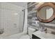 Well-lit bathroom with a shower-tub combo, decorative wood-look accent wall and charming round mirror at 827 E Minnesota St, Indianapolis, IN 46203