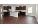 Open kitchen with hardwood floors, a large island, modern appliances, and dark cabinets at 8404 Alcona Dr, Indianapolis, IN 46237