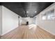 Open basement space with vinyl flooring, white walls, black paneled ceiling, with a kitchenette area at 9111 Sand Key Ln, Indianapolis, IN 46256