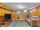 Basement with wood paneling, vinyl flooring, a couch, and a television at 1061 N Layman Ave, Indianapolis, IN 46219