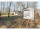 View of house featuring a storage shed, compact porch, and clean neutral siding, all set in a treed outdoor setting at 10614 W Hickory Ct, Quincy, IN 47456