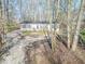 Single-story house featuring a front porch, gravel driveway, and surrounded by mature trees at 10614 W Hickory Ct, Quincy, IN 47456