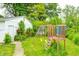 A backyard play structure sits near a quaint garage, accented by climbing greenery and blooming roses at 11416 Stoeppelwerth Dr, Indianapolis, IN 46229
