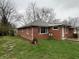 Back of house shows brick exterior with grassy backyard and some trees at 1509 N Mann Ave, Muncie, IN 47304