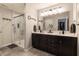 Bathroom featuring a double vanity with dark cabinets, a large mirror, and a glass-enclosed shower at 15493 Kennewick, Noblesville, IN 46062