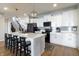 Bright kitchen with white cabinets, a gray backsplash, and black appliances and a large island with seating at 15493 Kennewick, Noblesville, IN 46062