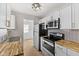 Modern kitchen featuring white cabinets, butcher block countertops, stainless appliances, and stylish backsplash at 1836 N Riley Ave, Indianapolis, IN 46218
