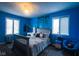Stylish bedroom with vibrant blue walls, a comfortable bed, and natural light from two windows at 3037 Santiago Dr, Greenwood, IN 46143