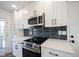 Updated kitchen features stainless steel appliances, white cabinets, a dark backsplash, and quartz countertops at 3260 Eddy Ct, Indianapolis, IN 46214