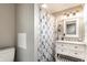 Well-lit bathroom showcasing a vanity with storage, stylish mirror, and a shower with patterned curtain at 421 S East St, Plainfield, IN 46168