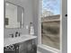 Modern bathroom with a black framed mirror and white countertop vanity next to window at 46 N Denny St, Indianapolis, IN 46201