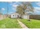 Large backyard with grassy lawn, storage shed, fence, and mature trees at 555 Leeds Ave, Indianapolis, IN 46203