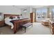 Bright bedroom features a wooden bed frame, bench, soft carpet, and natural light from large windows at 5710 Dapple Trce, Indianapolis, IN 46228