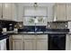 Bright kitchen featuring stainless steel sink, black appliances, mosaic tile backsplash, and light wood cabinetry at 5710 Dapple Trce, Indianapolis, IN 46228
