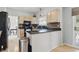 Kitchen showcasing stone countertops, black appliances, natural wood flooring, and a breakfast bar at 5710 Dapple Trce, Indianapolis, IN 46228
