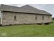 Side exterior view of a brick home showcasing well-maintained landscaping at 6089 W Hellis Dr, Muncie, IN 47304
