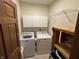 This laundry room has a washer, dryer, white cabinets, tile floors, and a wooden shelf at 6089 W Hellis Dr, Muncie, IN 47304