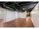 Spacious basement featuring modern flooring and exposed ceiling with painted rafters and duct work at 6120 Norwaldo Ave, Indianapolis, IN 46220