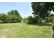 Large backyard featuring a grassy lawn with scattered trees, providing ample space for outdoor recreation at 7421 Rogers Dr, Indianapolis, IN 46214