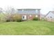 View of the rear exterior of the house featuring a brick facade, door, and a spacious backyard at 7421 Rogers Dr, Indianapolis, IN 46214