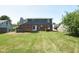 View of the home's rear exterior, deck, and large, grassy backyard perfect for outdoor activities at 7421 Rogers Dr, Indianapolis, IN 46214