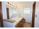 Spacious bathroom with long vanity, large mirror, sconce lighting, and a window at 7421 Rogers Dr, Indianapolis, IN 46214
