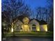 Elegant home with a stone facade, beautifully landscaped yard, and warm lighting at dusk at 7957 Preservation Dr, Indianapolis, IN 46278