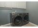 Well-lit laundry room features updated washer and dryer and convenient overhead cabinet storage at 7957 Preservation Dr, Indianapolis, IN 46278