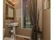 Cozy powder room with a pedestal sink, decorative mirror, and elegant window treatments at 7957 Preservation Dr, Indianapolis, IN 46278
