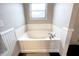 A white tub with chrome hardware is set within a tiled alcove with a window above at 8201 E 250 S, Zionsville, IN 46077